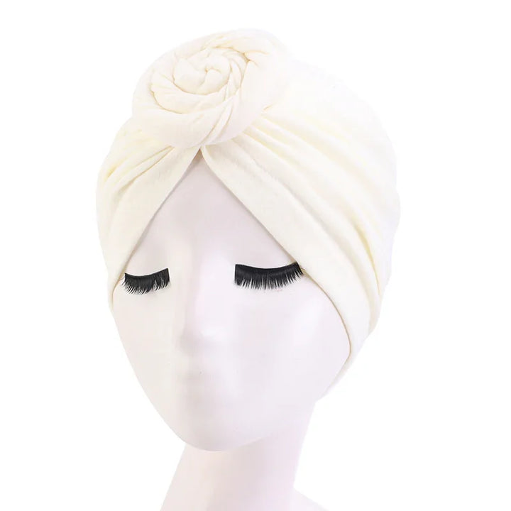 White turban headwrap with rose detail on mannequin with long eyelashes