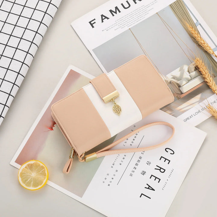 Beige and white wristlet wallet with gold leaf charm on magazines and lemon slice