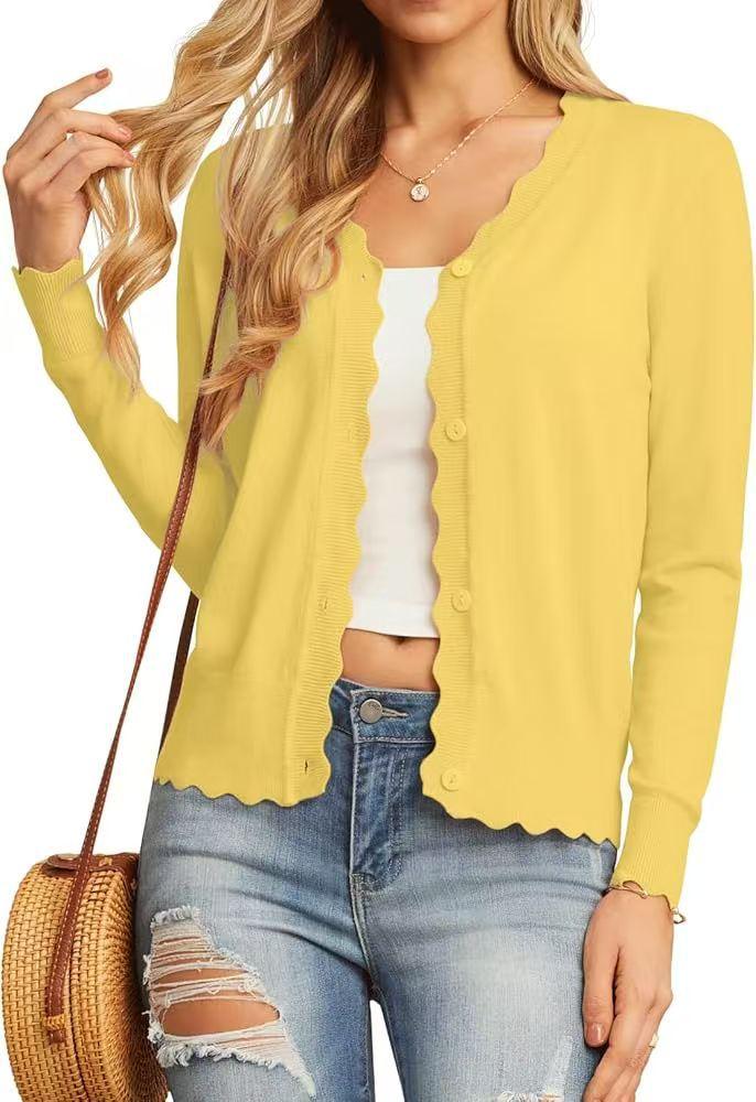 Woman wearing yellow scalloped edge cardigan with white crop top and distressed jeans, carrying a wicker bag