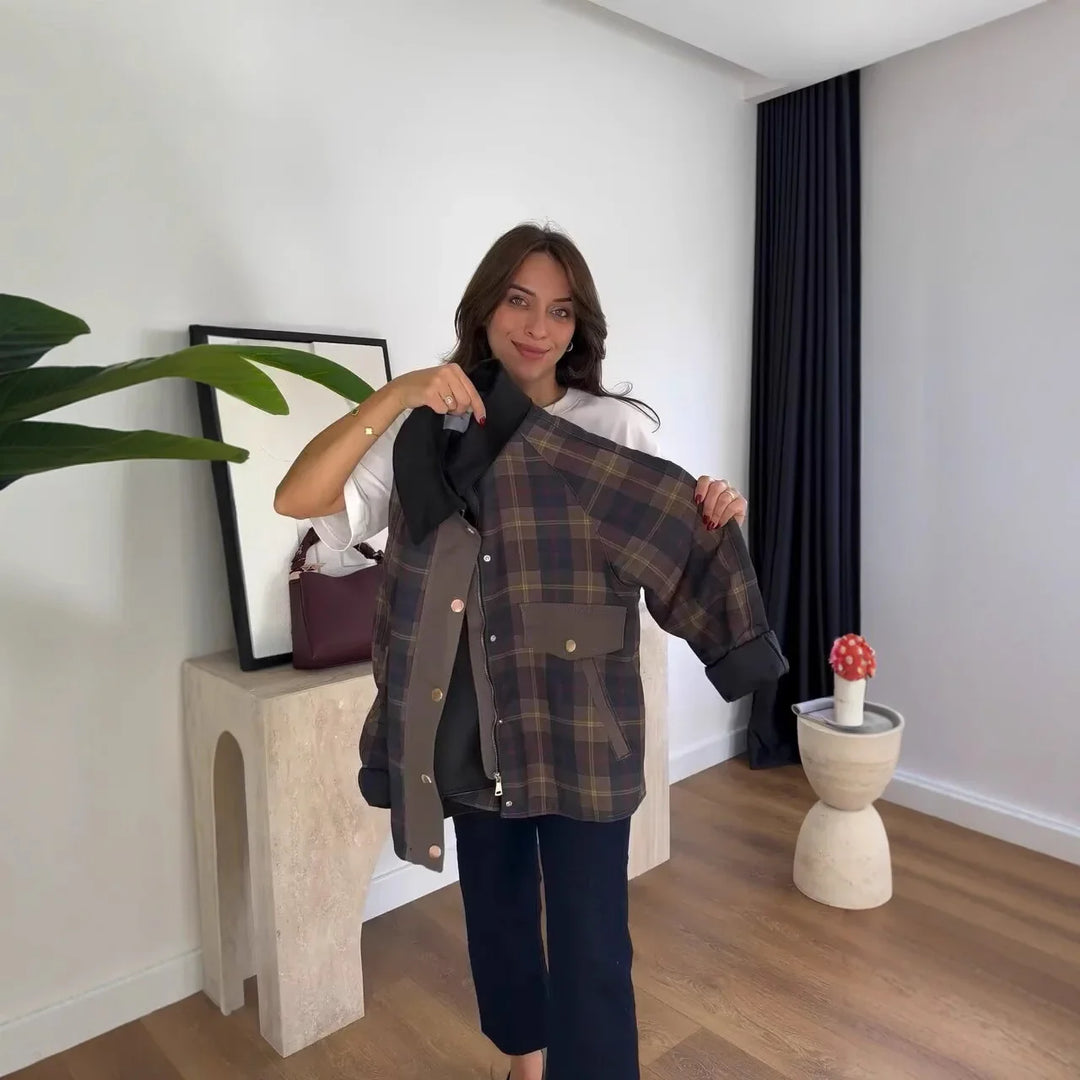 Woman holding a brown plaid jacket with pockets in a modern room with wooden floor and plants