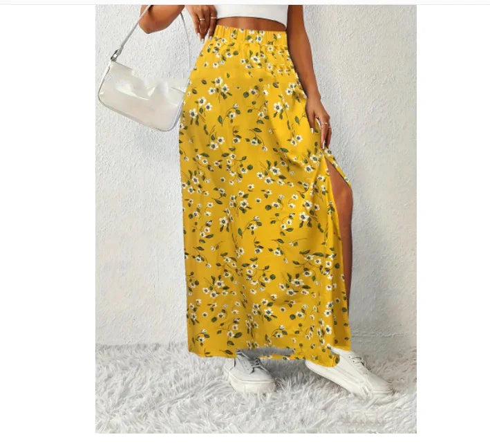 Woman wearing yellow floral maxi skirt with side slit, white crop top, white sneakers, and white handbag