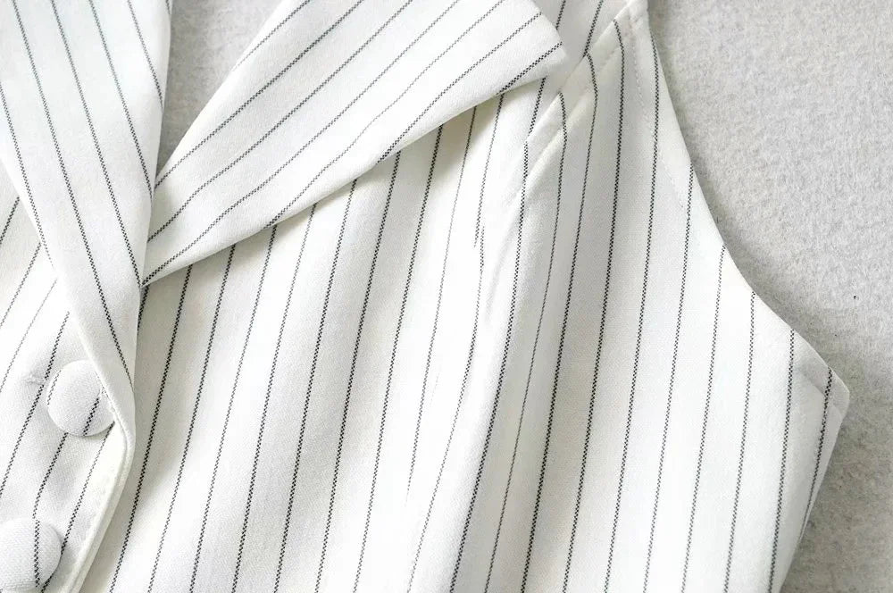 Close-up of white pinstripe blazer with lapel collar and fabric-covered buttons on grey background