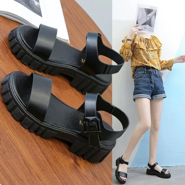 Black platform sandals with chunky soles displayed on wood, worn with denim shorts and yellow floral blouse