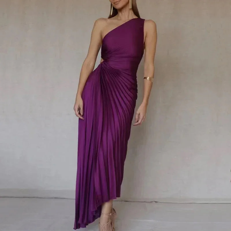 Woman wearing a purple one-shoulder pleated asymmetrical evening dress with gold arm cuff and heels