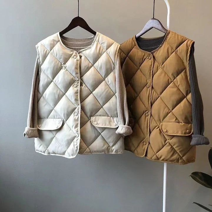 Two quilted sleeveless vests in beige and brown layered over rolled-up long sleeve sweaters on hangers