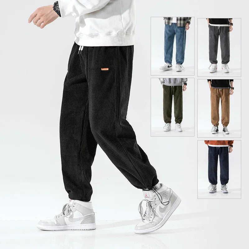 Men's casual corduroy jogger pants in black, blue, gray, green, brown, and navy modeled with sneakers