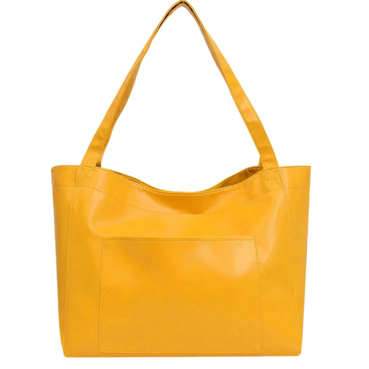 Yellow leather tote bag with front pocket and shoulder straps on white background