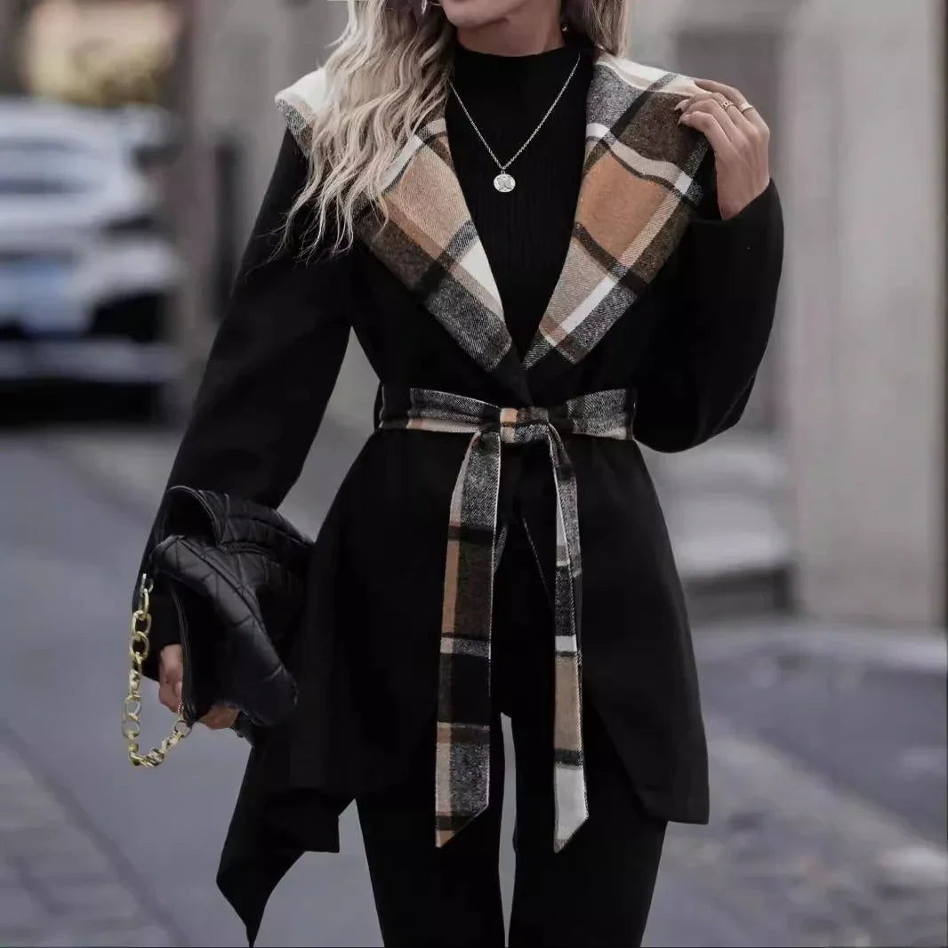 Woman wearing black coat with large plaid collar and matching belt, holding black quilted handbag