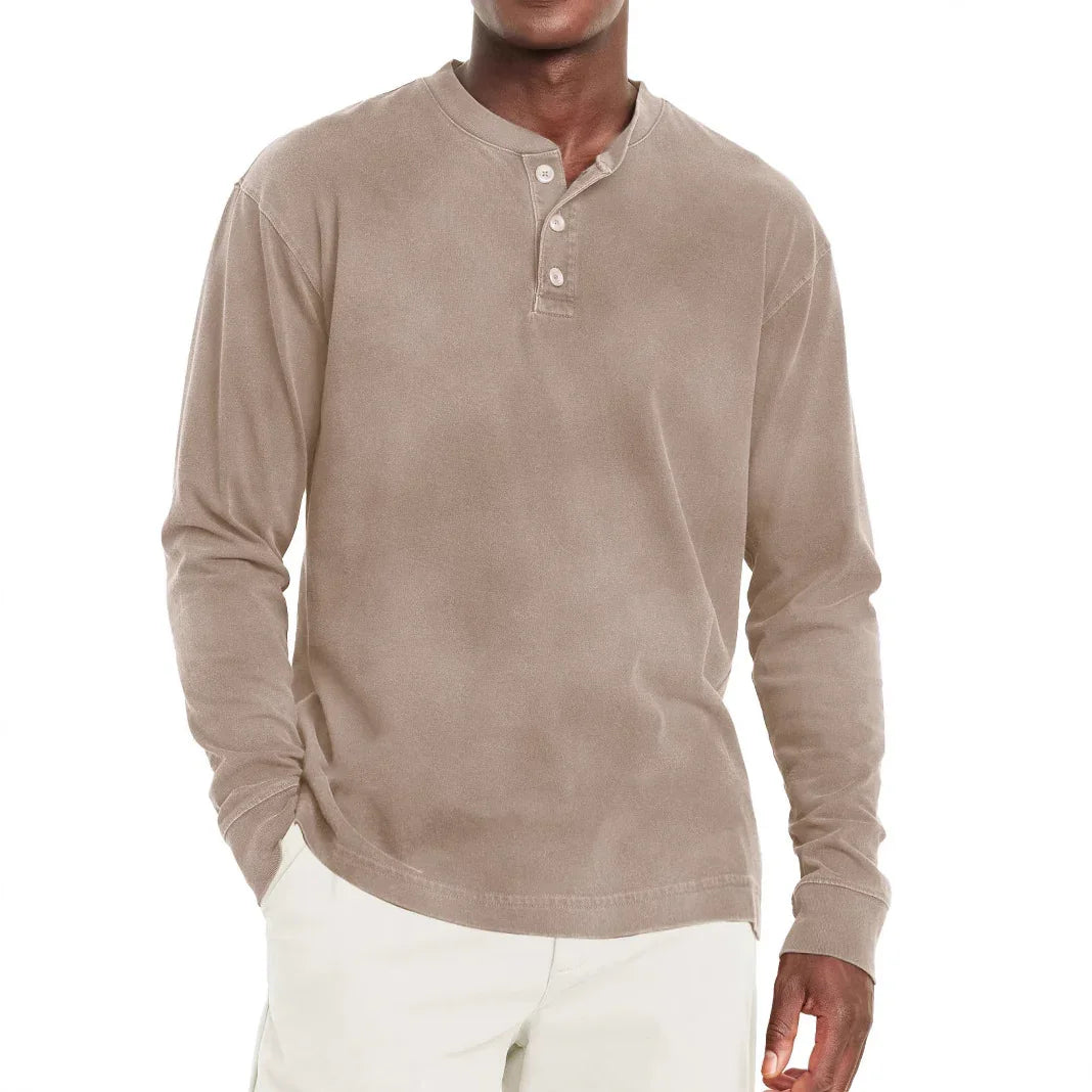 Men's beige long sleeve henley shirt with three buttons, styled casually with white pants