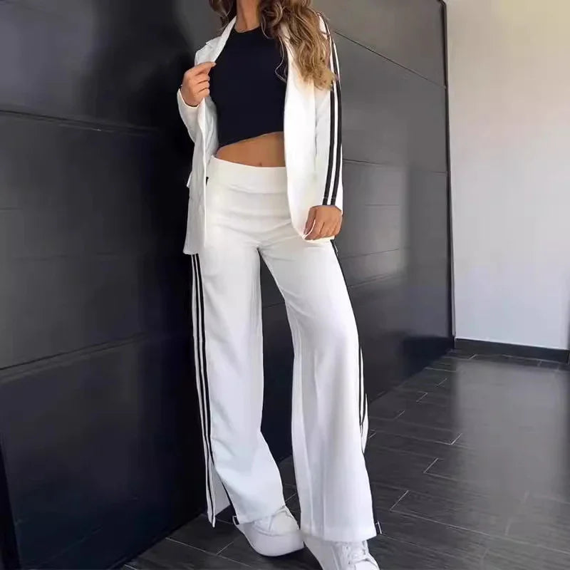 Woman wearing white striped wide-leg pants and matching jacket with black crop top and white sneakers
