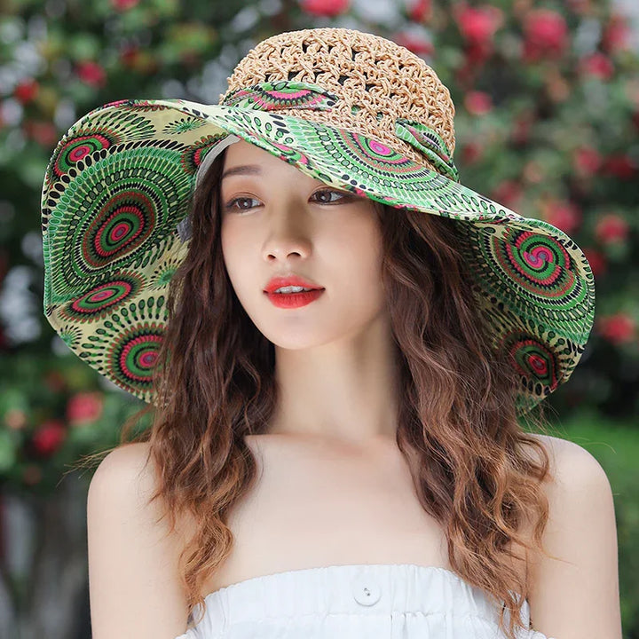 Young woman with wavy hair wearing a wide-brimmed green patterned sun hat and white strapless top outdoors