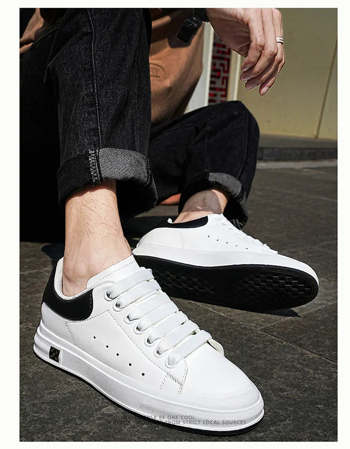 White casual sneakers with black heel detail worn with rolled-up black jeans on pavement