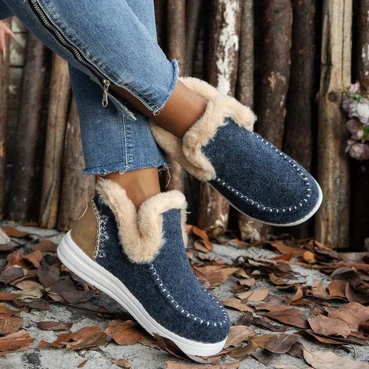 Cozy navy blue slip-on winter shoes with beige fur lining and white sole, worn with jeans