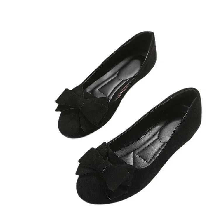Pair of black ballet flats with large decorative bows and cushioned insoles on white background