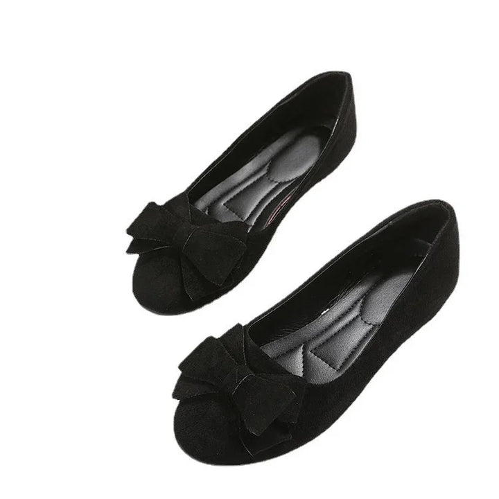 Pair of black ballet flats with large decorative bows and cushioned insoles on white background