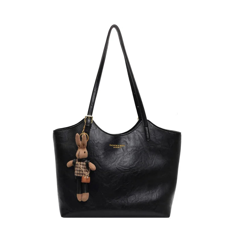 Black leather tote bag with long handles and attached brown bunny keychain accessory
