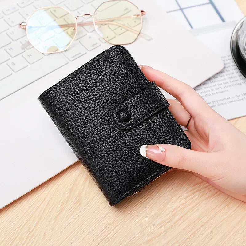 Black textured leather wallet held by hand on wooden desk with keyboard and glasses