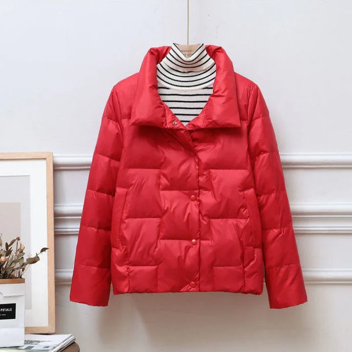 Red quilted puffer jacket on striped turtleneck displayed on hanger against white wall
