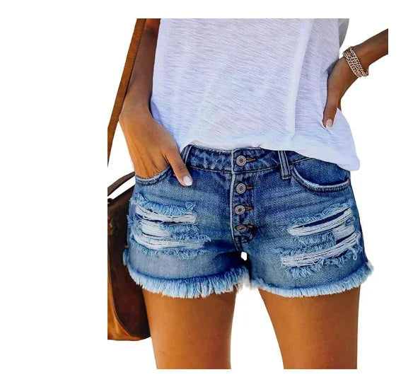 woman wearing distressed blue denim shorts with frayed hems and a white casual top