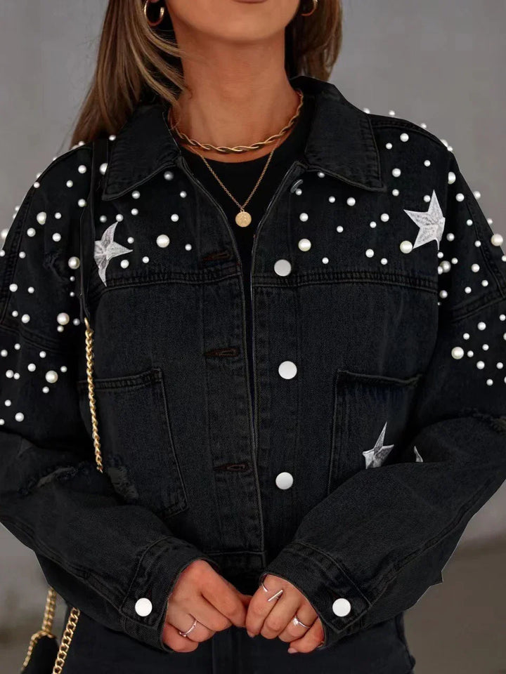 Black denim jacket with pearl embellishments and star patches worn with gold jewelry and rings