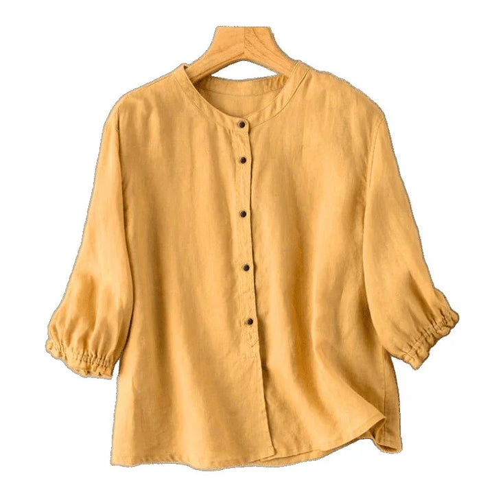 Mustard yellow linen blouse with round neck, button-down front, and elastic cuff sleeves on hanger