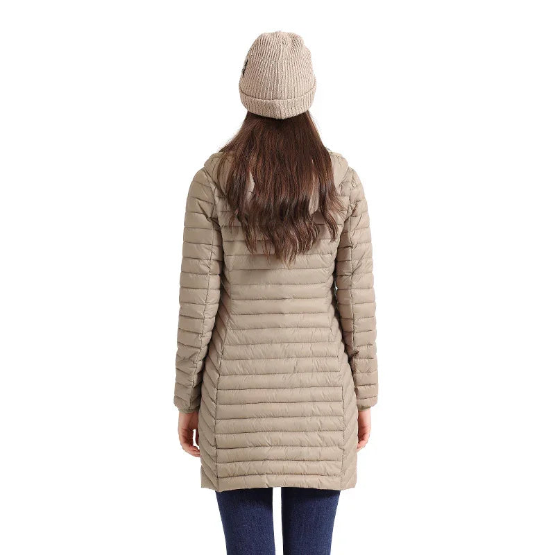 Woman wearing beige quilted puffer coat and knit beanie hat, viewed from back on white background