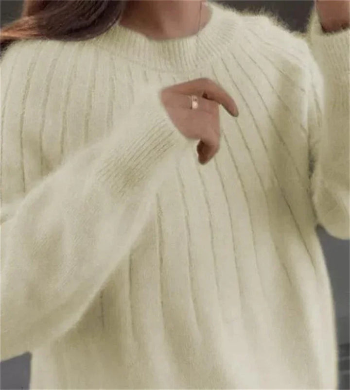 Close-up of woman wearing a soft cream knit sweater with vertical ribbing and long sleeves