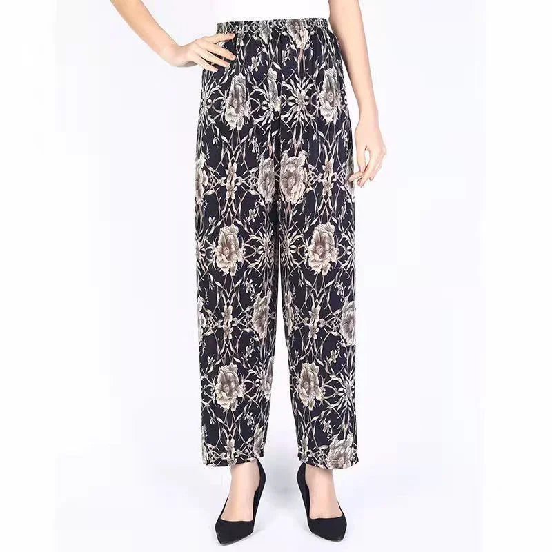 Women’s black floral print wide-leg pants paired with black heels on white background