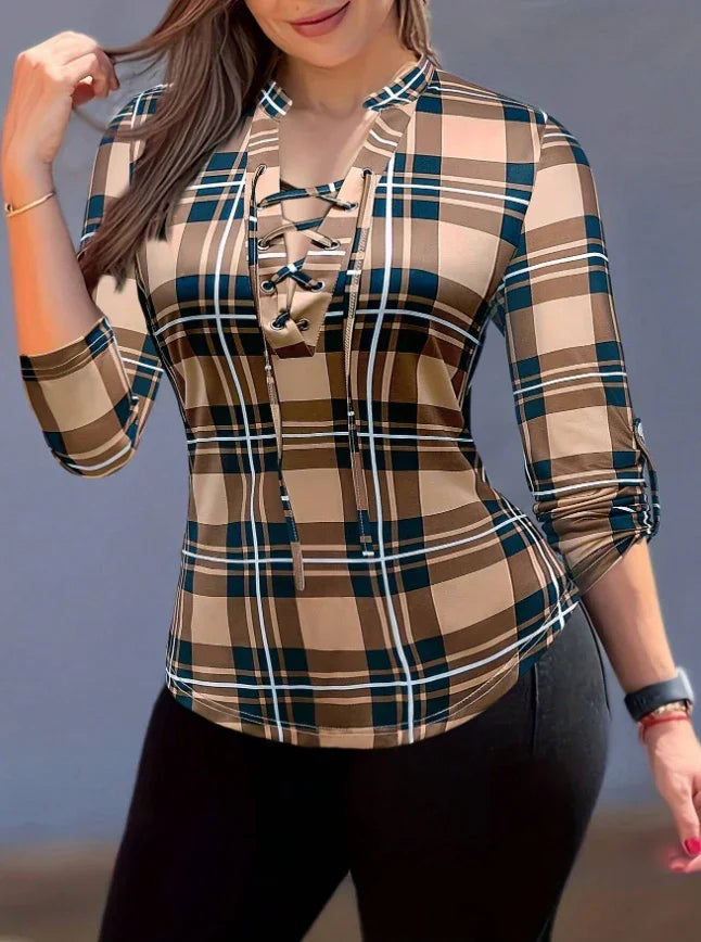 Woman wearing a fitted brown and navy plaid lace-up long sleeve top with rolled sleeves