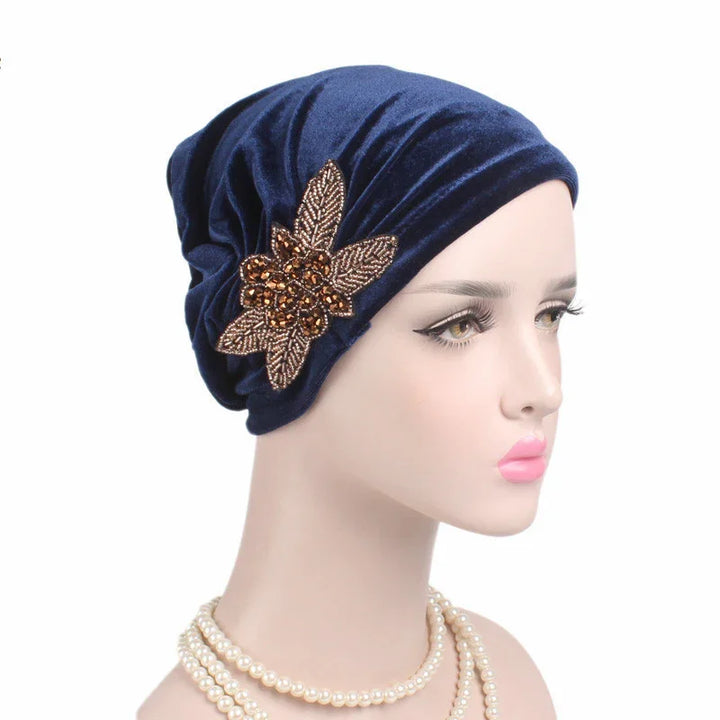 Mannequin wearing navy blue velvet turban with gold beaded leaf brooch and pearl necklace