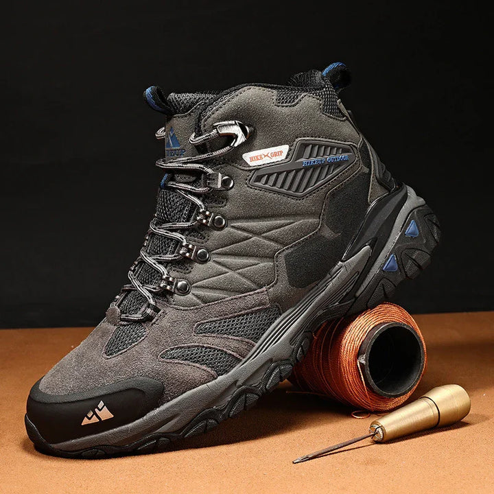 Gray and black hiking boot with steel toe, rugged sole, and hiking gear on brown surface