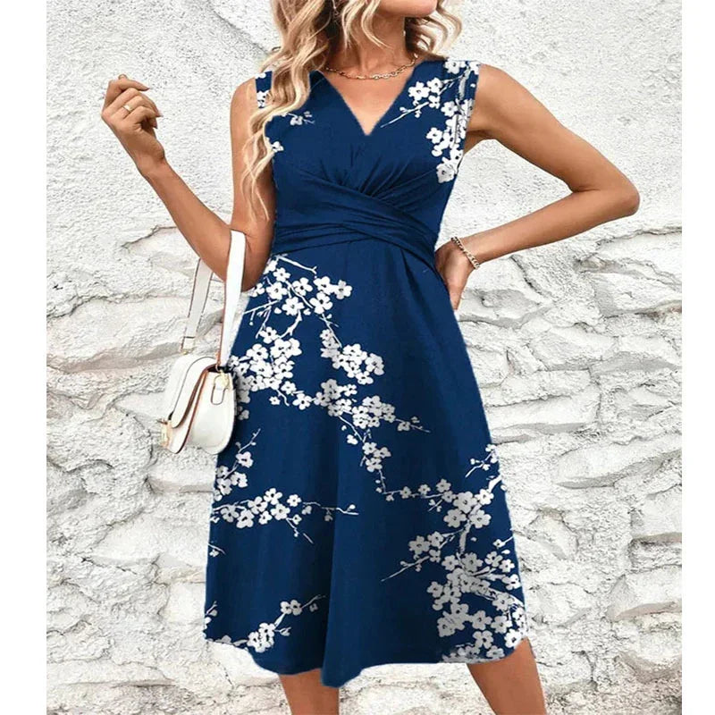 Woman wearing sleeveless navy blue floral dress with white flower print and white handbag