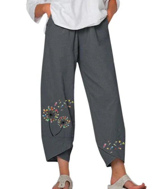 Gray cropped pants with colorful dandelion flower print near cuffs, worn with white top and sandals