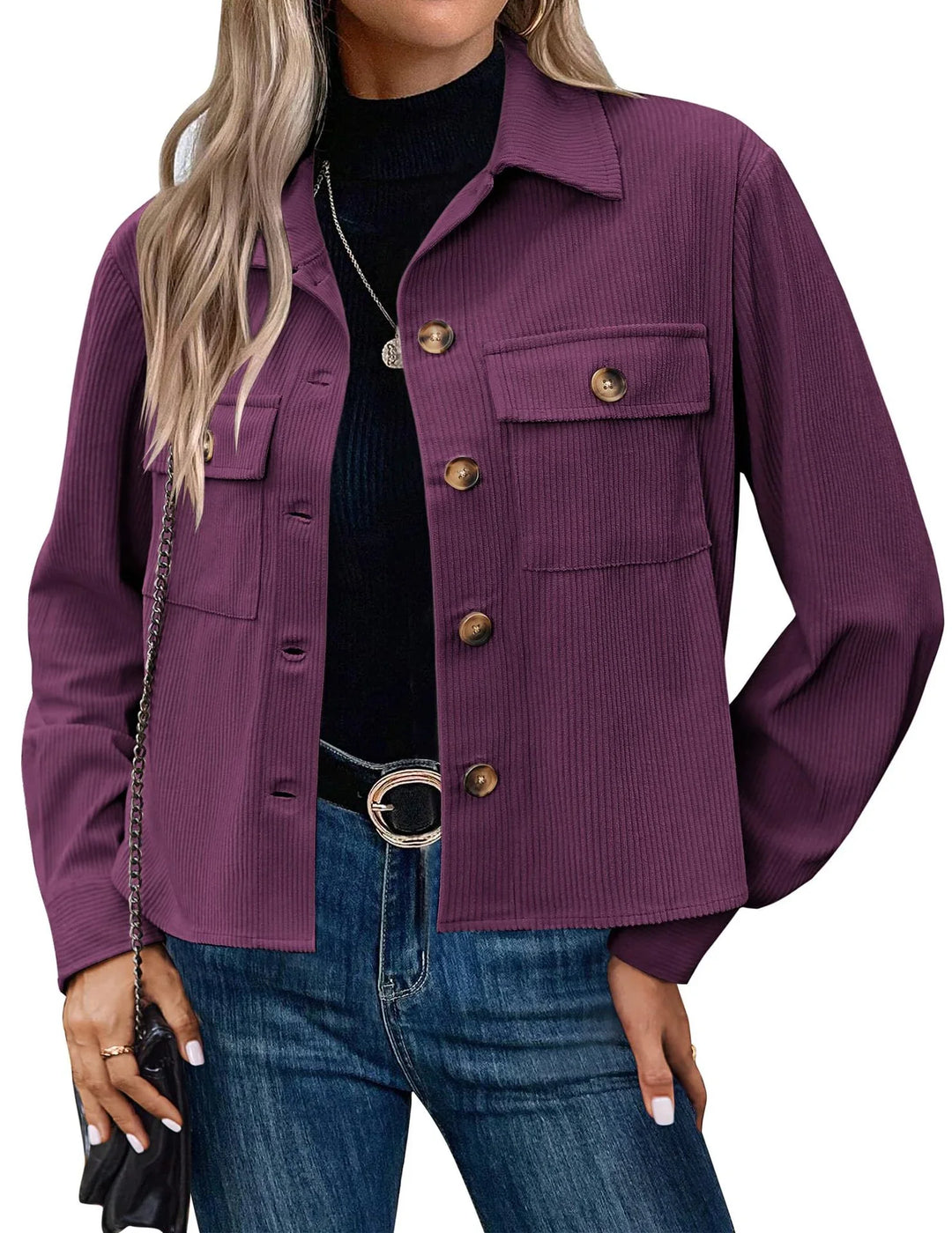 Woman wearing purple ribbed button-up jacket with flap pockets, black top, blue jeans, and belt