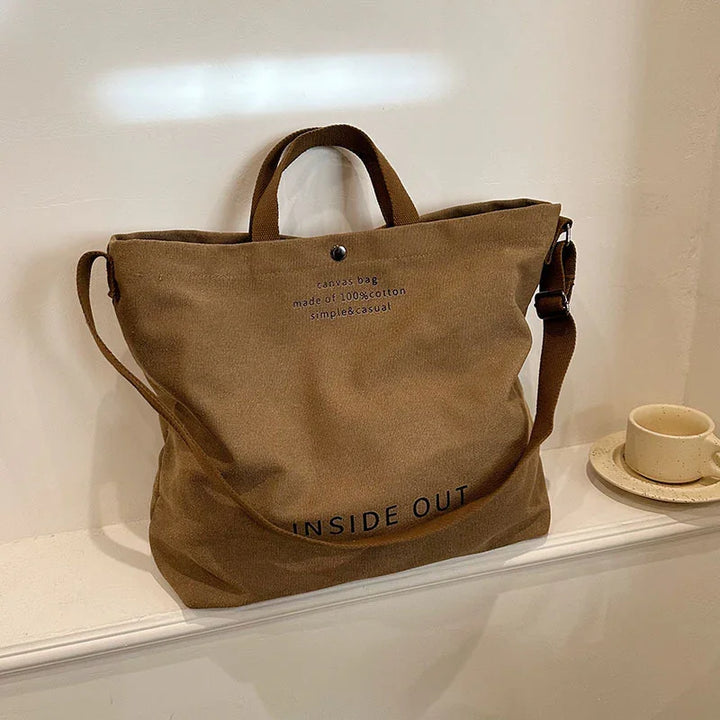 Brown canvas tote bag with 'INSIDE OUT' text, cotton material, simple casual style on white shelf