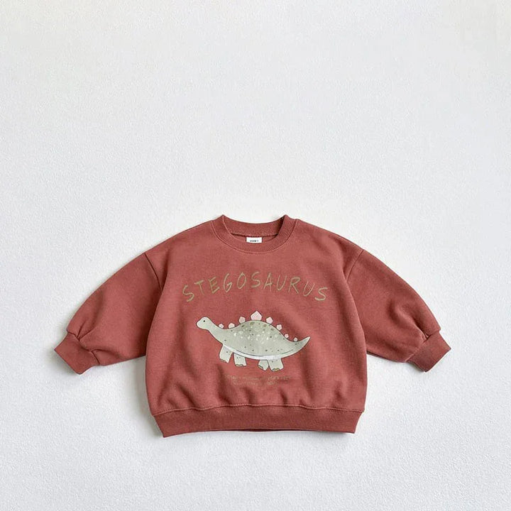 Rust-colored kids sweatshirt with a green Stegosaurus dinosaur graphic and text on front