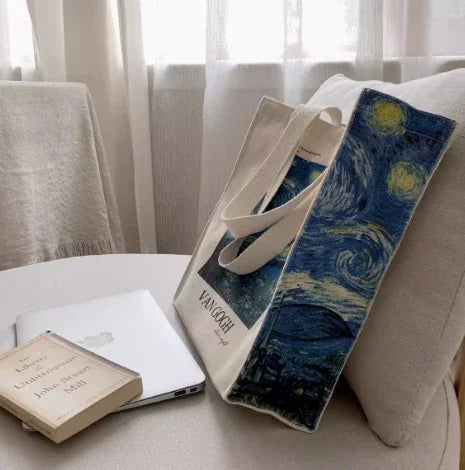 Van Gogh tote bag with Starry Night print on a chair beside a laptop and a book