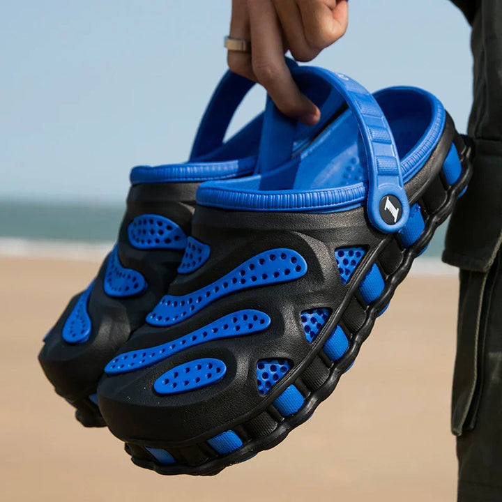 Hand holding blue and black ventilation holes slip-on beach shoes outdoors