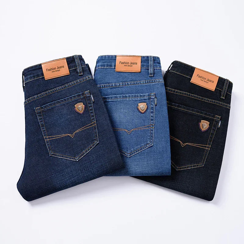 Three folded pairs of fashion jeans in dark, medium, and black denim with leather brand patches and stitched back pockets