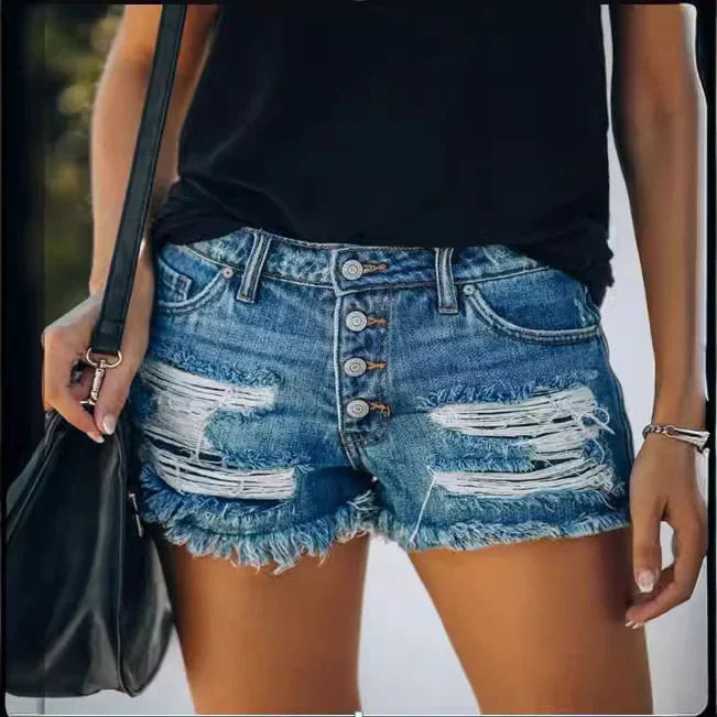 Woman wearing distressed button-fly denim shorts and black top, holding black bag