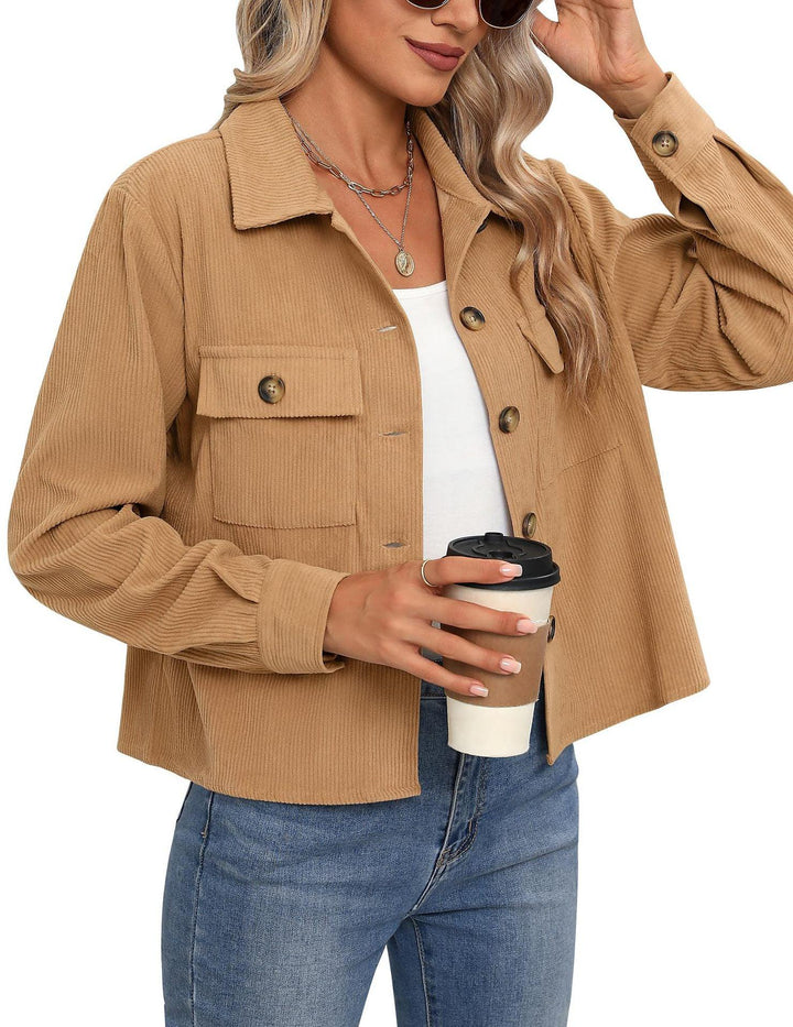 Woman wearing camel corduroy button-up jacket with pockets, blue jeans, white top, holding coffee cup