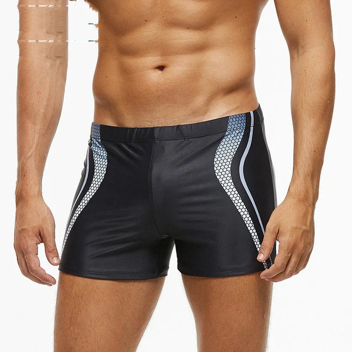 Fit male torso wearing black swim shorts with blue and white hexagonal side patterns