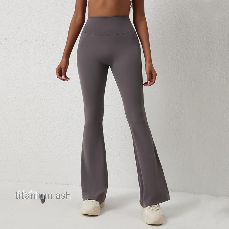 Woman wearing titanium ash high-waisted flare leggings with white sneakers against white wall