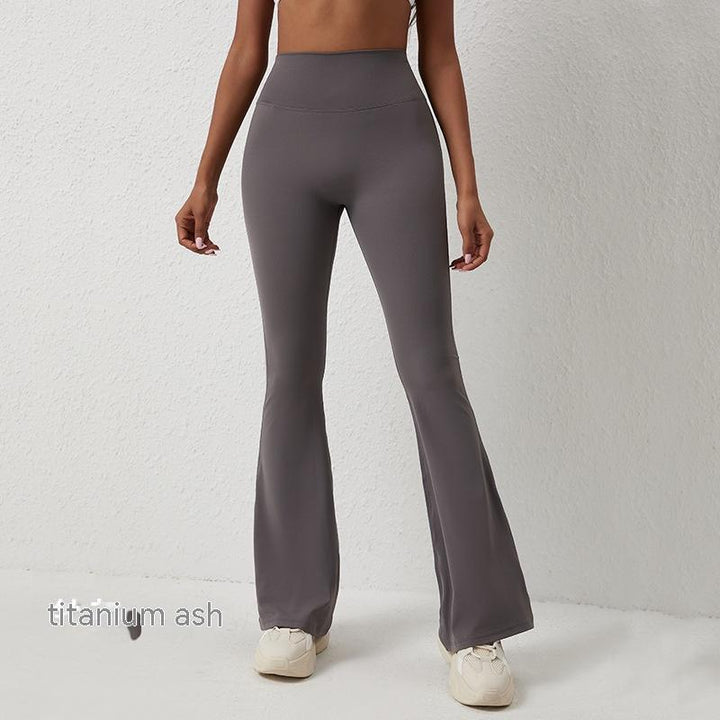 Woman wearing titanium ash high-waisted flare leggings with white sneakers against white wall