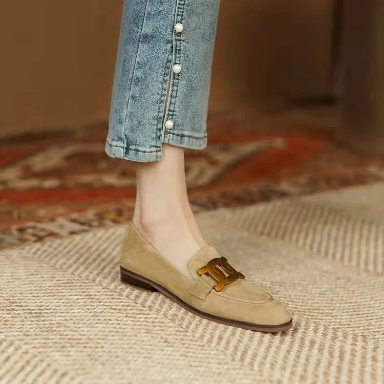 Beige suede loafer with gold buckle worn with cropped blue jeans featuring pearl buttons