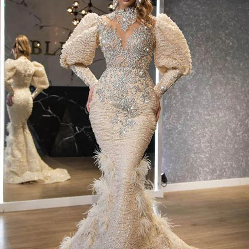 Elegant cream evening gown with puffed sleeves, silver embellishments, and feathered mermaid skirt in showroom