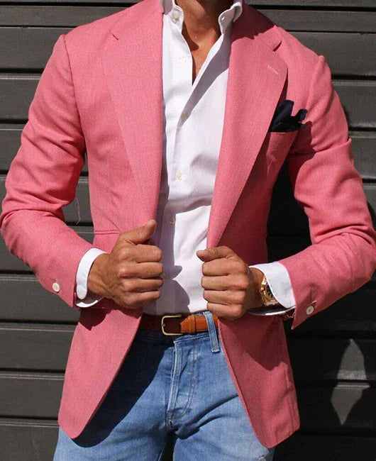 Man wearing a pink blazer with a white dress shirt and blue jeans, holding jacket lapels