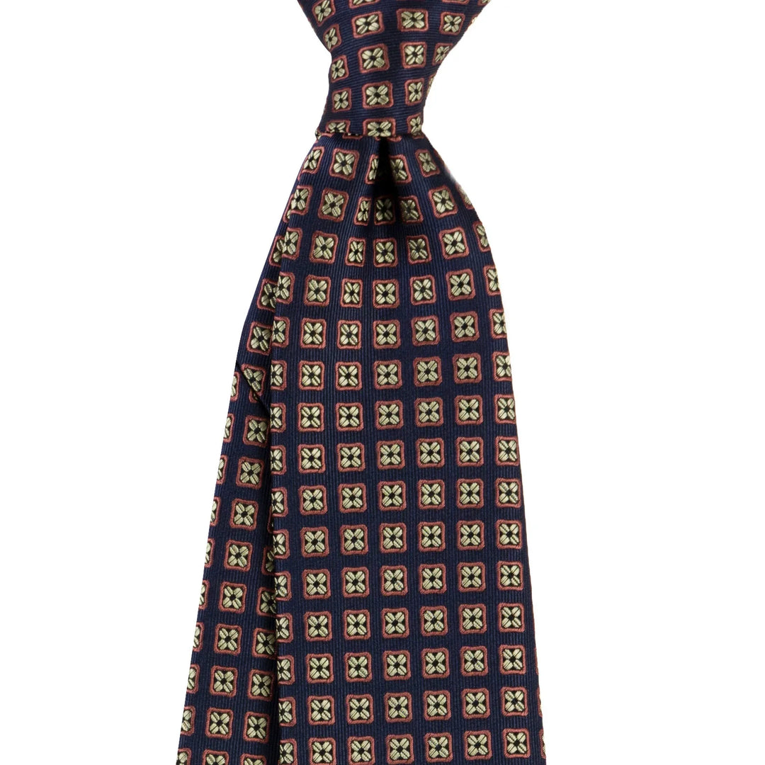 Navy blue silk tie with brown and beige geometric square pattern on white background