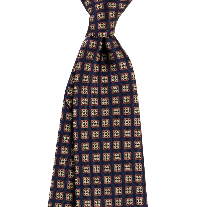 Navy blue silk tie with brown and beige geometric square pattern on white background