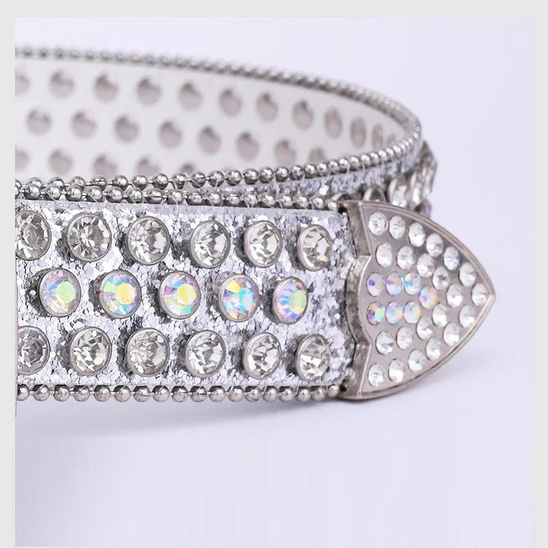 Close-up of a silver rhinestone-studded leather belt with metallic studs and a pointed tip